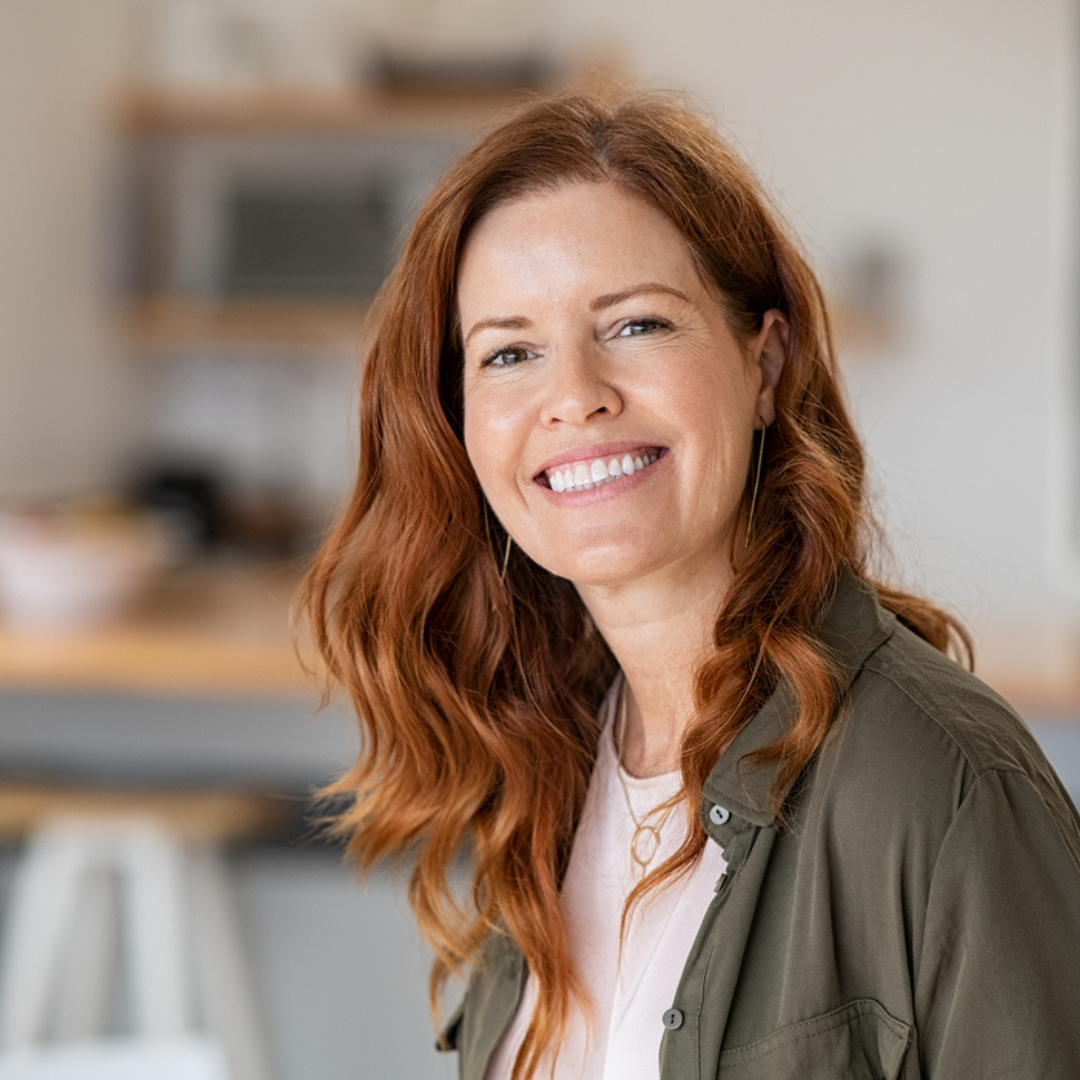 Woman with red hair smiling in a kitchen setting