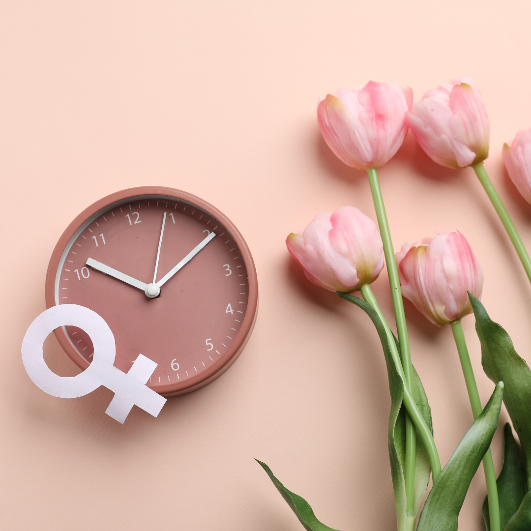 Pink clock with a female gender symbol and pink tulips on a beige background