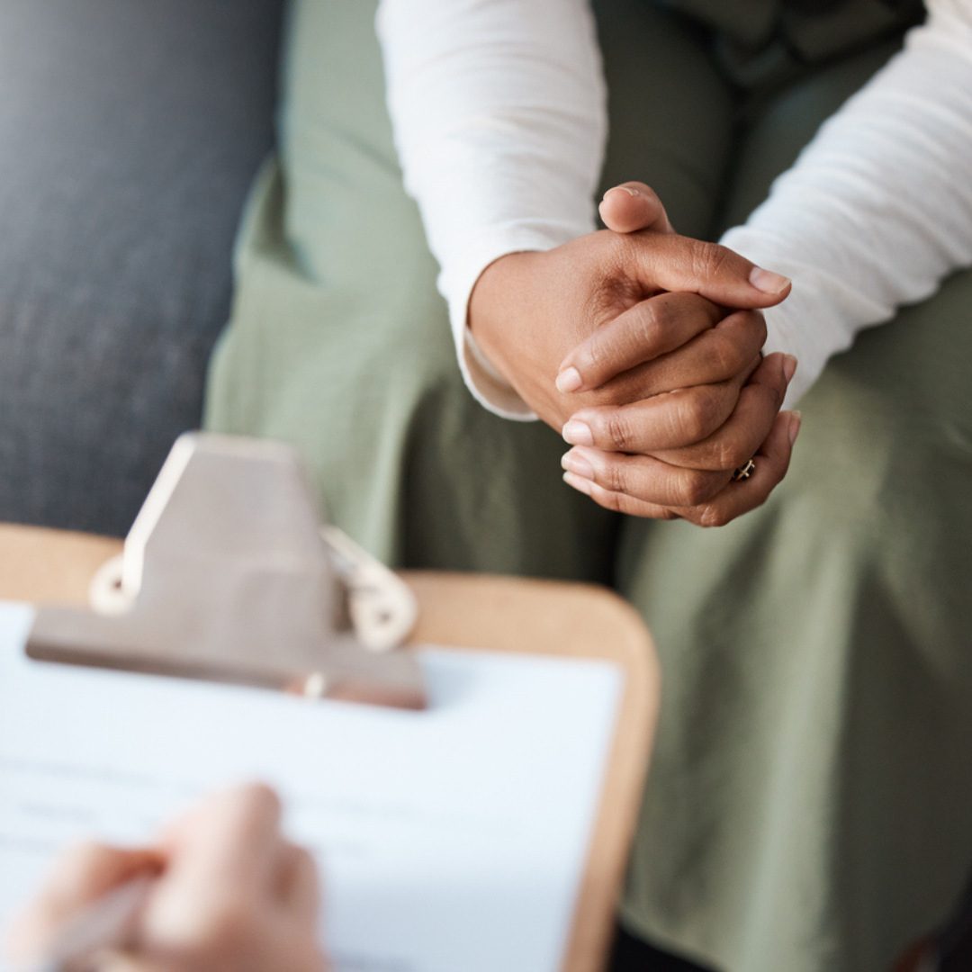 Person holding hands with a clipboard in the foreground